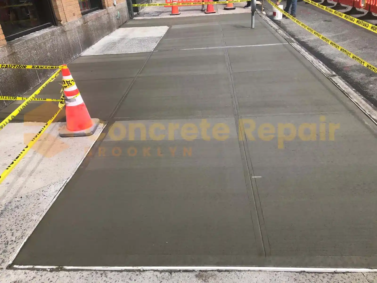 Concrete Sidewalk sloped for drainage, leading to a house, surrounded by grass and landscaping.
